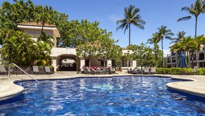 A swimming pool with lounge chairs and palm trees.