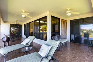 A covered outdoor area with lounge chairs, ceiling fans, and large windows.
