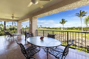 A covered patio with a round table and chairs, a ceiling fan, and a view of a golf course.