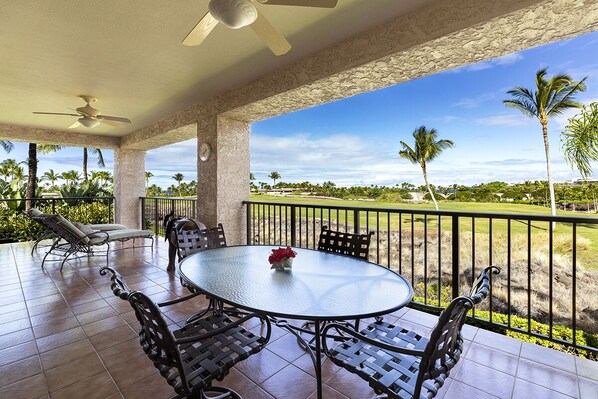 A covered patio with a round table and chairs, a ceiling fan, and a view of a golf course.