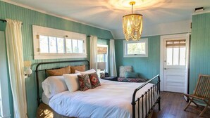 Un dormitorio con cama, una silla y una lámpara de araña.