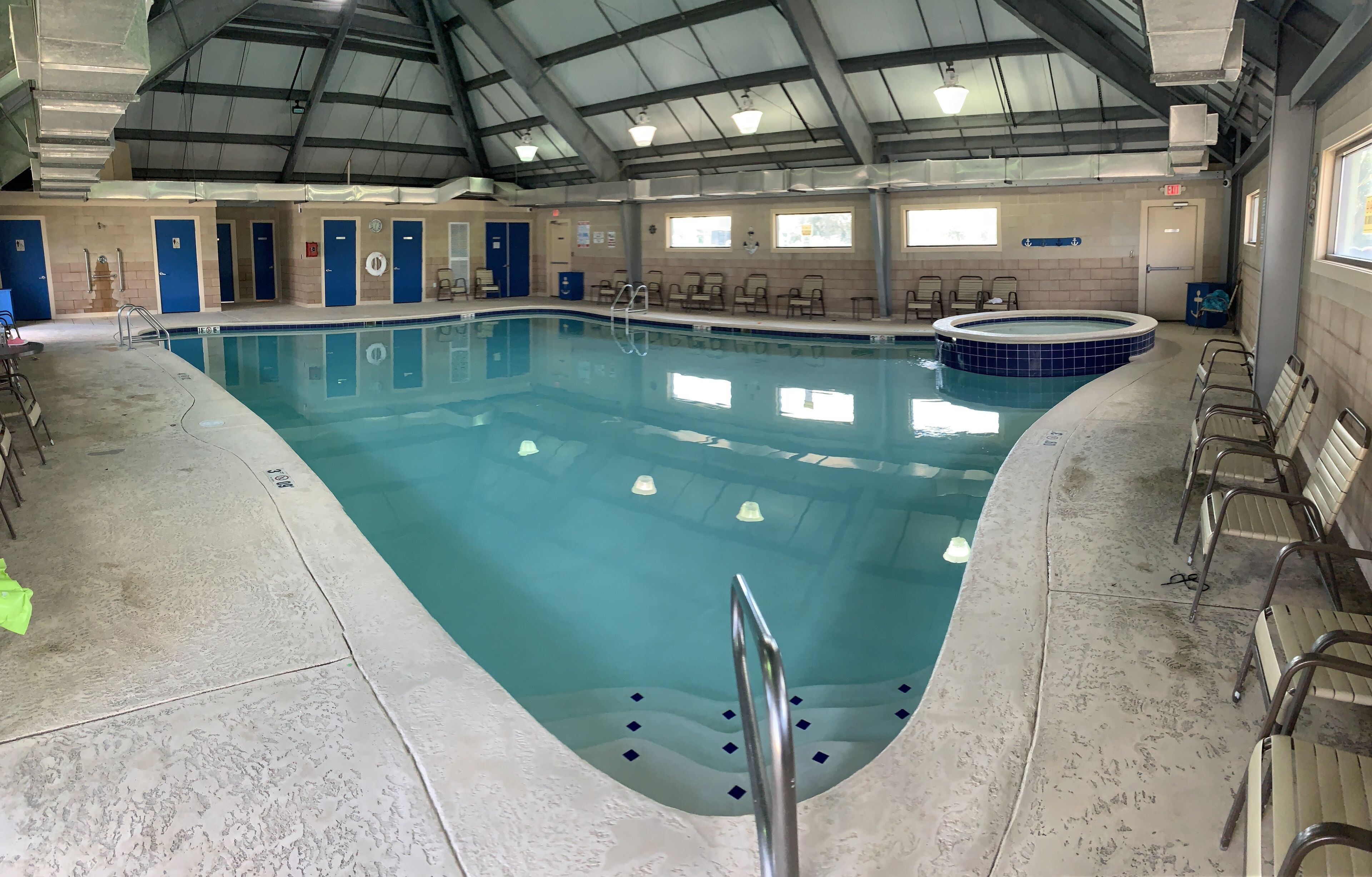 Una piscina interior con trampolín, sillas de descanso y jacuzzi.