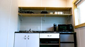 Cozinha compacta com armários brancos, micro-ondas, torradeira e geladeira.