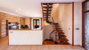 Una cocina moderna con una isla central, una escalera de madera y vistas al exterior.