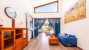 Una habitación con un armario de madera, un sofá azul, un cuadro y un reloj en la pared.