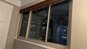 Une fenêtre donnant sur une vue panoramique de la ville la nuit.