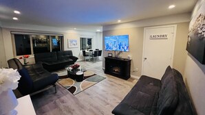 Un salon moderne avec une cheminée, un téléviseur et un coin repas.