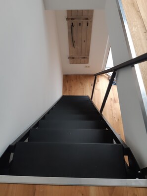 Staircase with a minimalist design, featuring a black handrail and wooden steps.