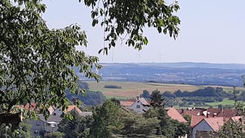 Paisaje rural con casas, árboles y turbinas eólicas a lo lejos.
