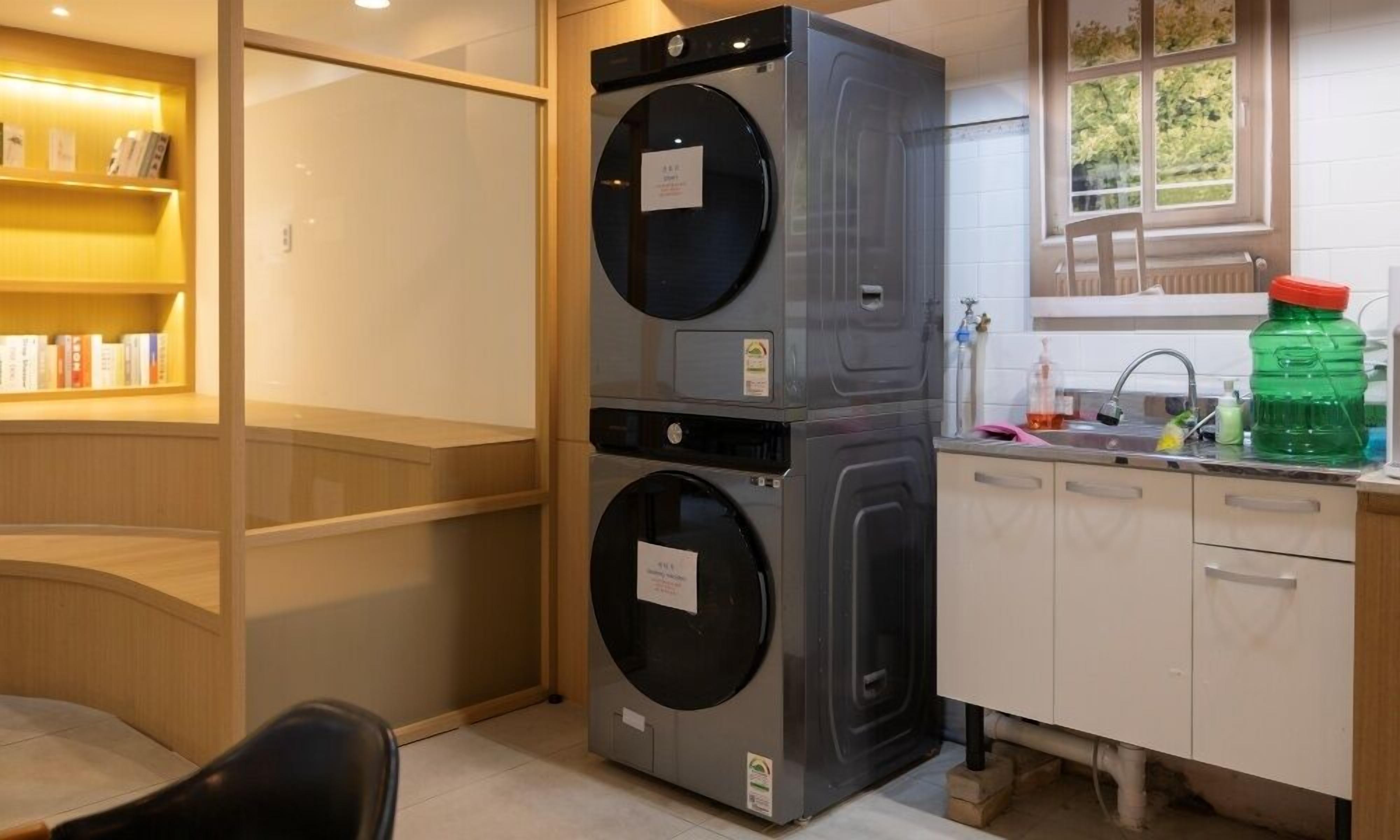 A compact kitchen with a built-in washer and dryer, a small sink, and a window with a view of greenery.