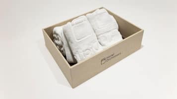 A wooden box containing folded white towels with embossed text, labeled "Hotel Dictionary."