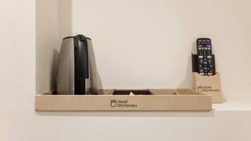 Caja tipo diccionario de hotel con un control remoto y un objeto doblado.
