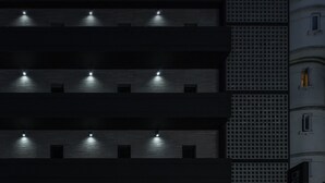 A multi-story building with evenly spaced balconies, each illuminated by a single light fixture. - Cheongju Hotel Dictionary (Cheongju)