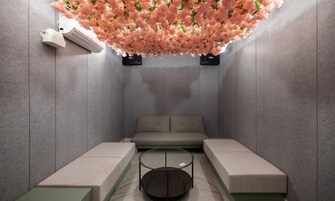 Un spa moderno con un sofá gris, una mesa de centro de vidrio y un techo decorado con flores rosadas.