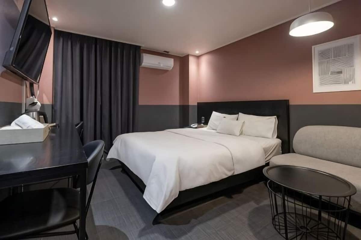 Una habitación de hotel con una cama, un sofá, un escritorio y una televisión.