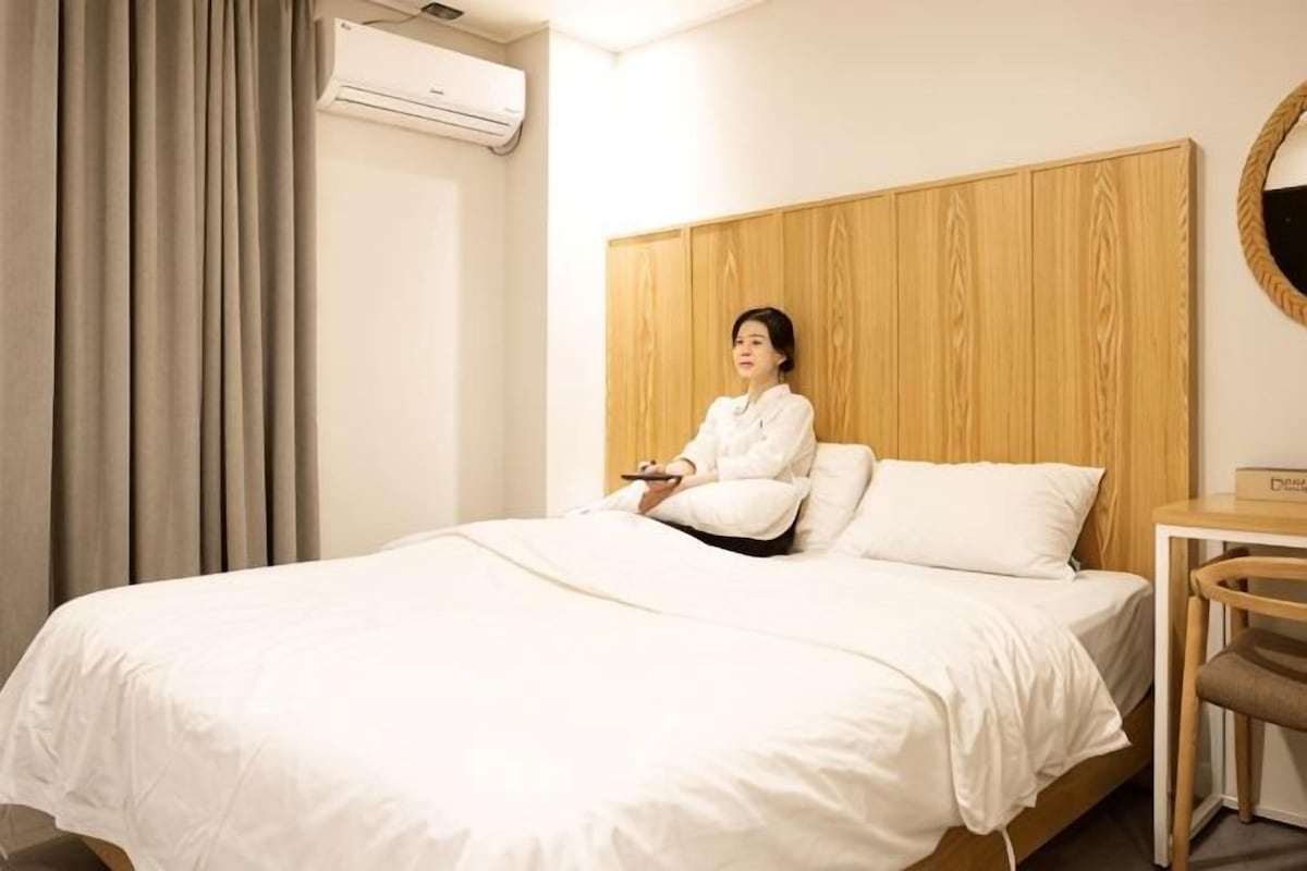 Une chambre d’hôtel équipée d’un lit, d’une tête de lit en bois, d’une table de chevet et d’un appareil de climatisation.