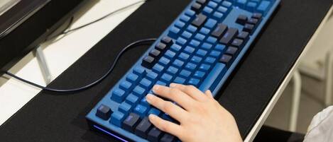 A person using a blue mechanical keyboard on a black desk.