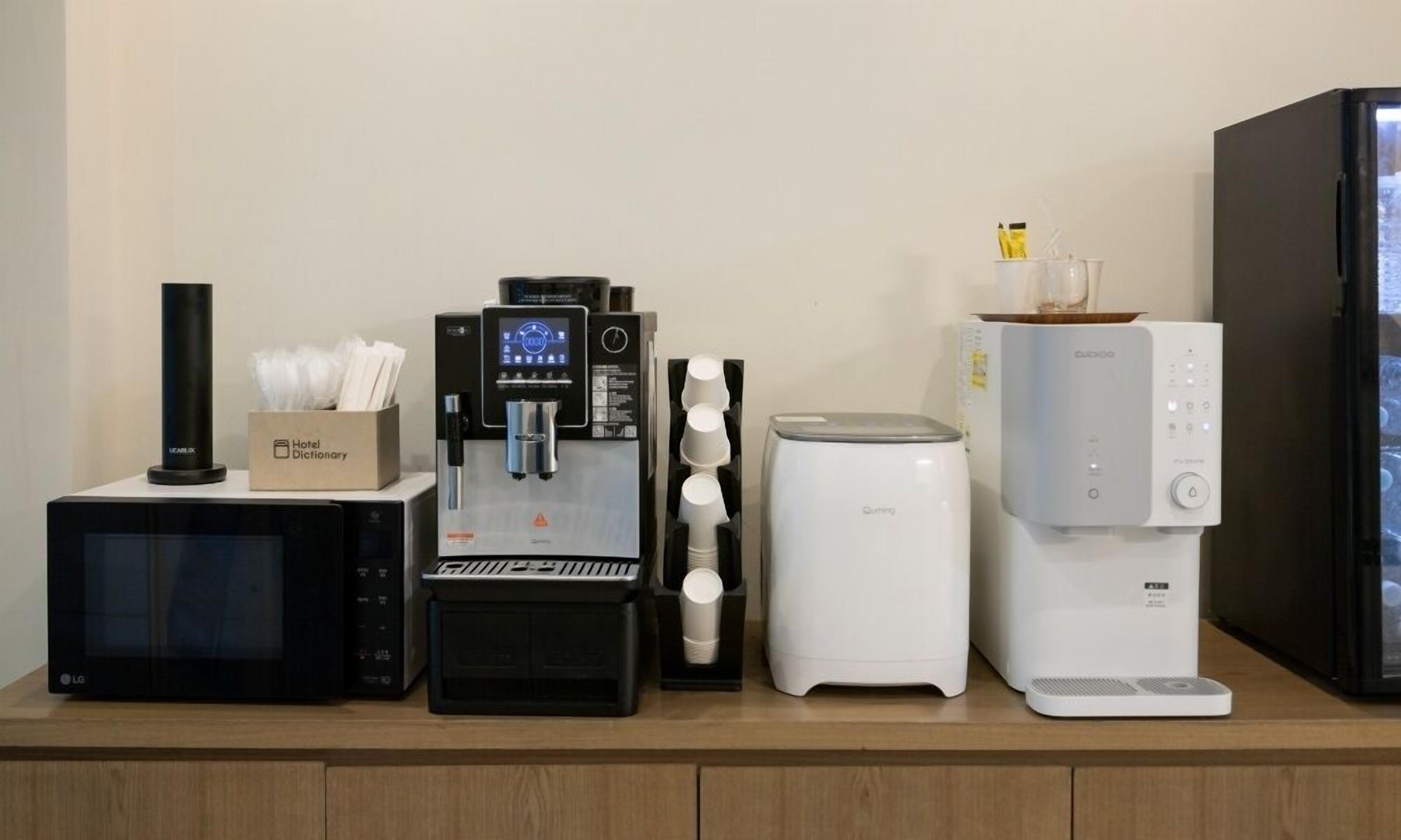 Una cafetera, un microondas y un refrigerador sobre una encimera.