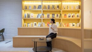 A modern library with a curved seating area and a glass table. Shelves are filled with books and magazines. - Cheongju Hotel Dictionary (Cheongju)