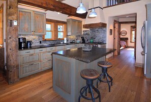 A kitchen with wooden cabinets, a large island with stools, and a refrigerator. - Elk Ave Luxury, Gorgeous 3+ BR Custom Home in CB (Crested Butte)