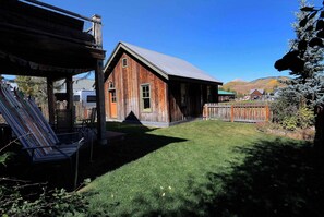 A rustic wooden building with a sloped roof, a fenced yard, and a clear blue sky. - Elk Ave Luxury, Gorgeous 3+ BR Custom Home in CB (Crested Butte)