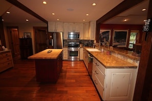 A modern kitchen with wooden cabinets, stainless steel appliances, and a large island.