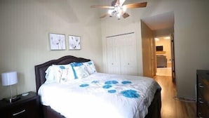 A bedroom with a bed, a nightstand, a ceiling fan, and a door leading to another room. - Culberhouse Cottage - Executive/Vacation Rental (Jonesboro)