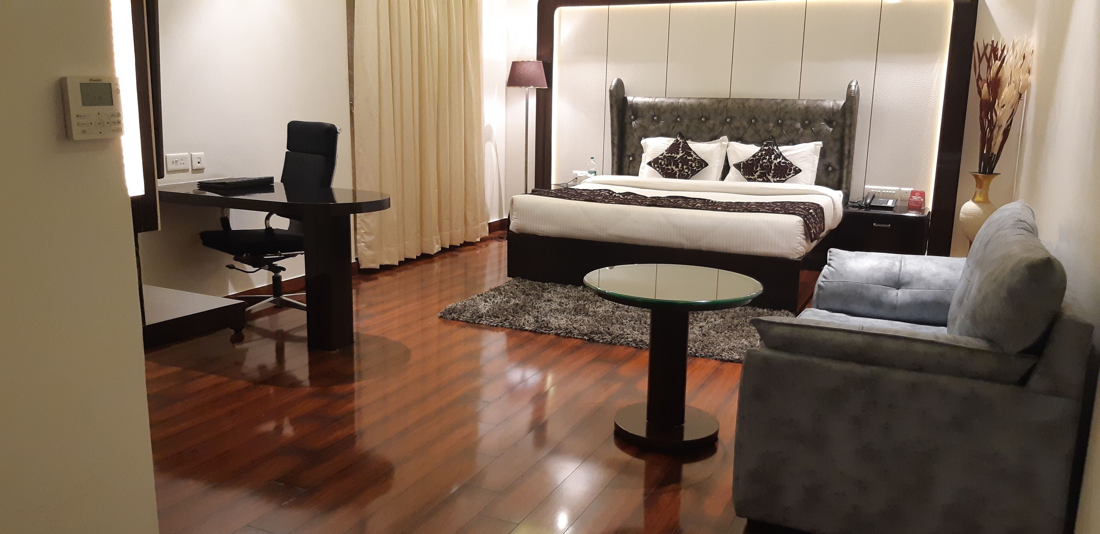 A hotel room with a bed, a desk, a chair, and a sofa.