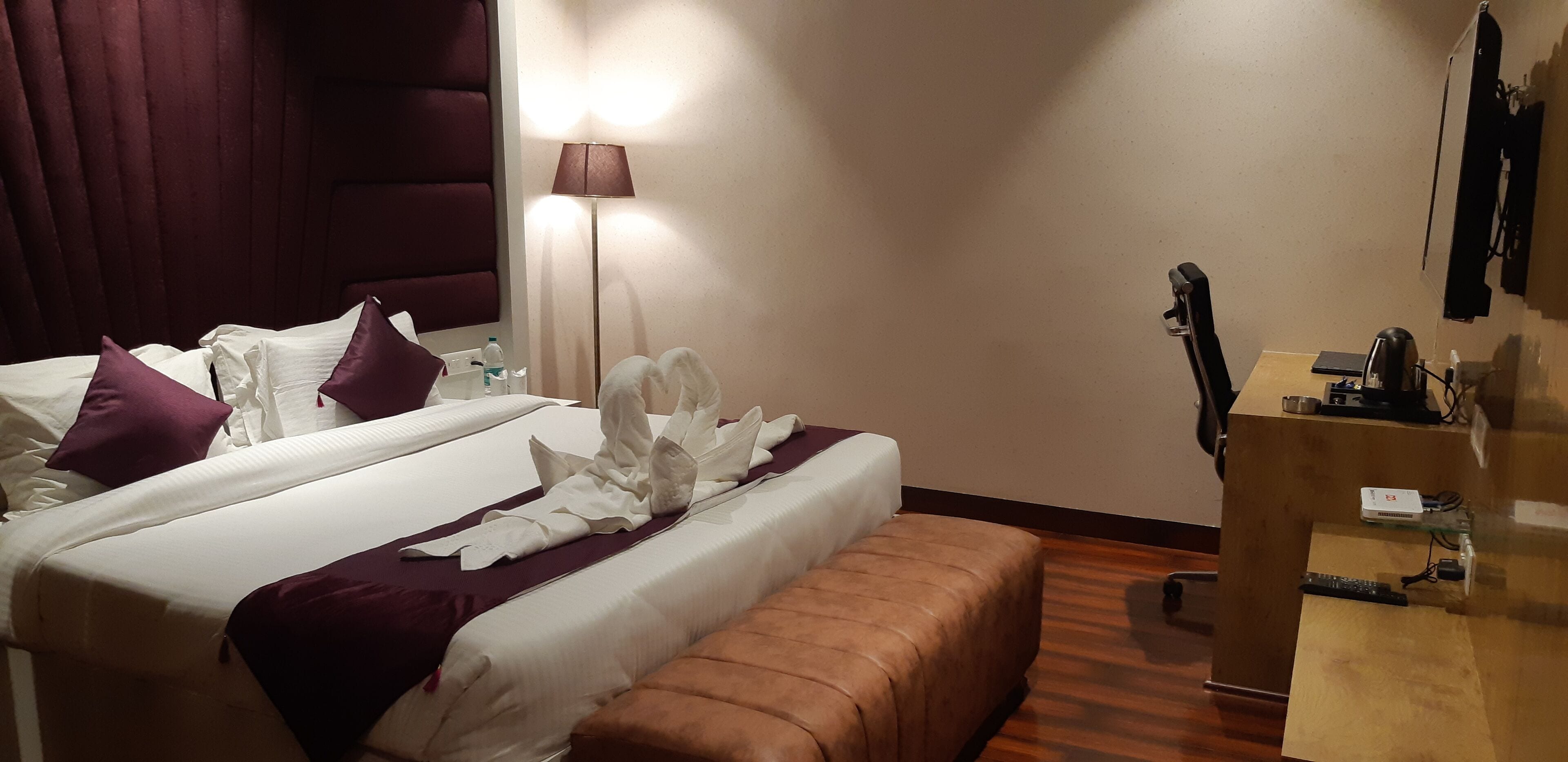 A hotel room with two beds, a desk, a lamp, and a wardrobe.