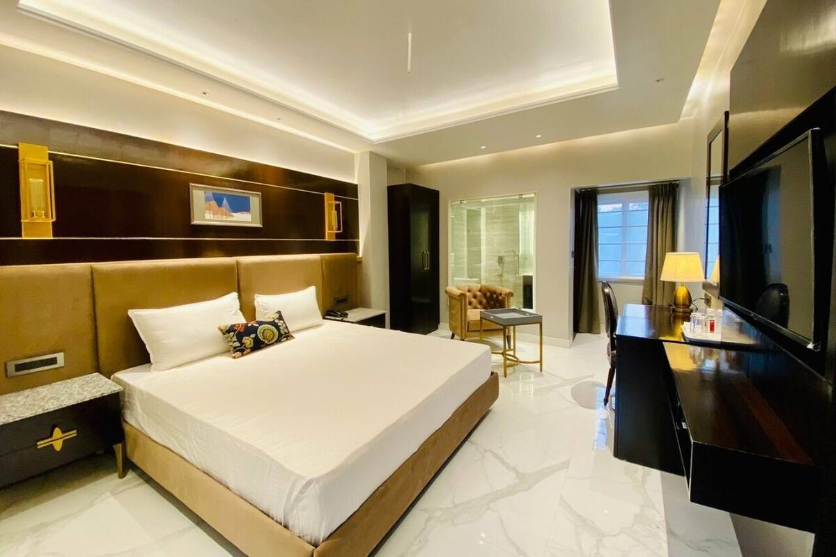 A hotel room with a large bed, a desk, a television, and a window with curtains.