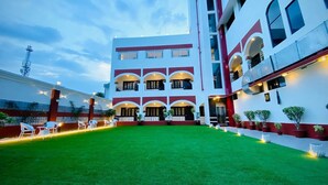 A multi-story hotel with a central courtyard, balconies, and outdoor seating. - Prayag Inn (Prayagraj)