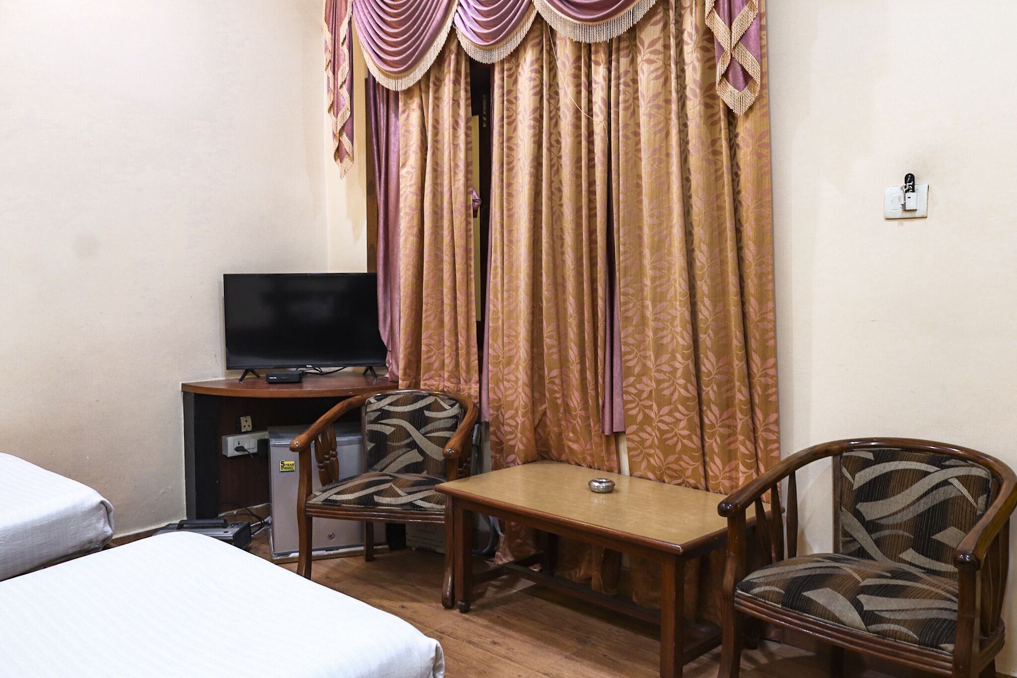 A hotel room with two beds, a desk with a computer, a television, and a chair.