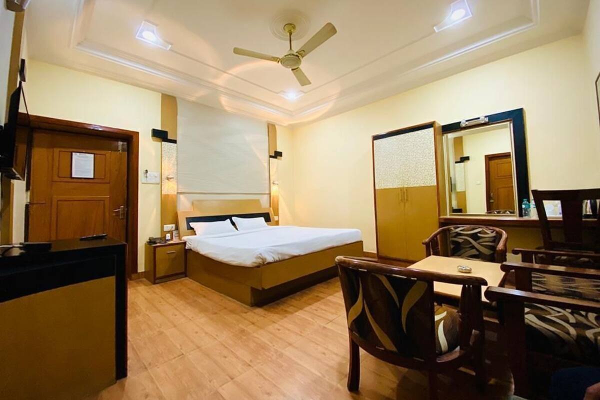 A hotel room with a bed, bedside table, chair, desk, and a ceiling fan.