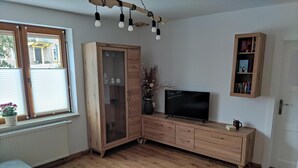 A living room with wooden furniture, a TV, and a window with blinds. - Vacation apartment Hartmann (Gohrisch)