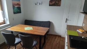 A compact kitchen with a wooden table and chairs, a bench, and a sink. - Vacation apartment Hartmann (Gohrisch)