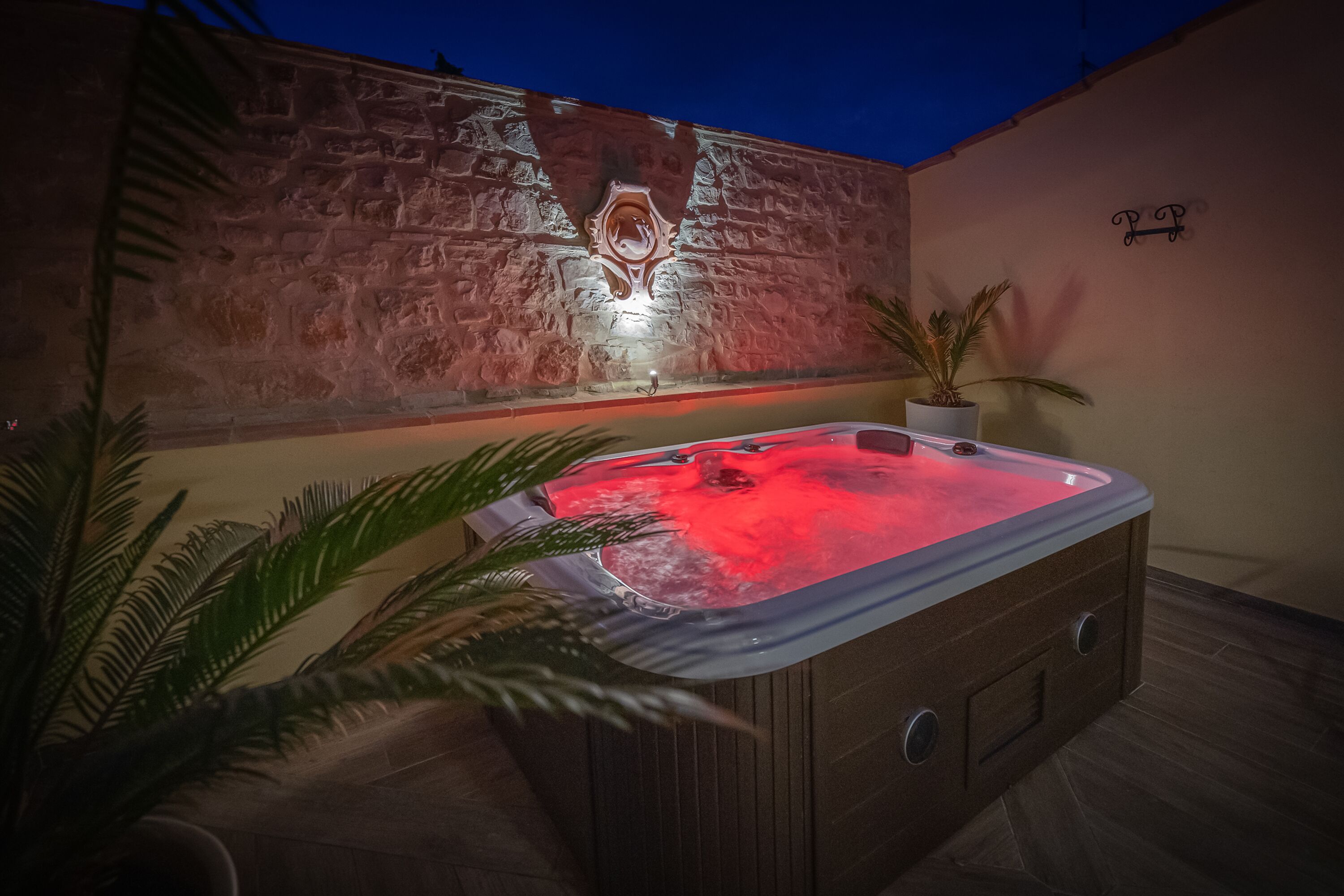 Un bain à remous avec un mur en pierre en arrière-plan et une petite plante en pot.