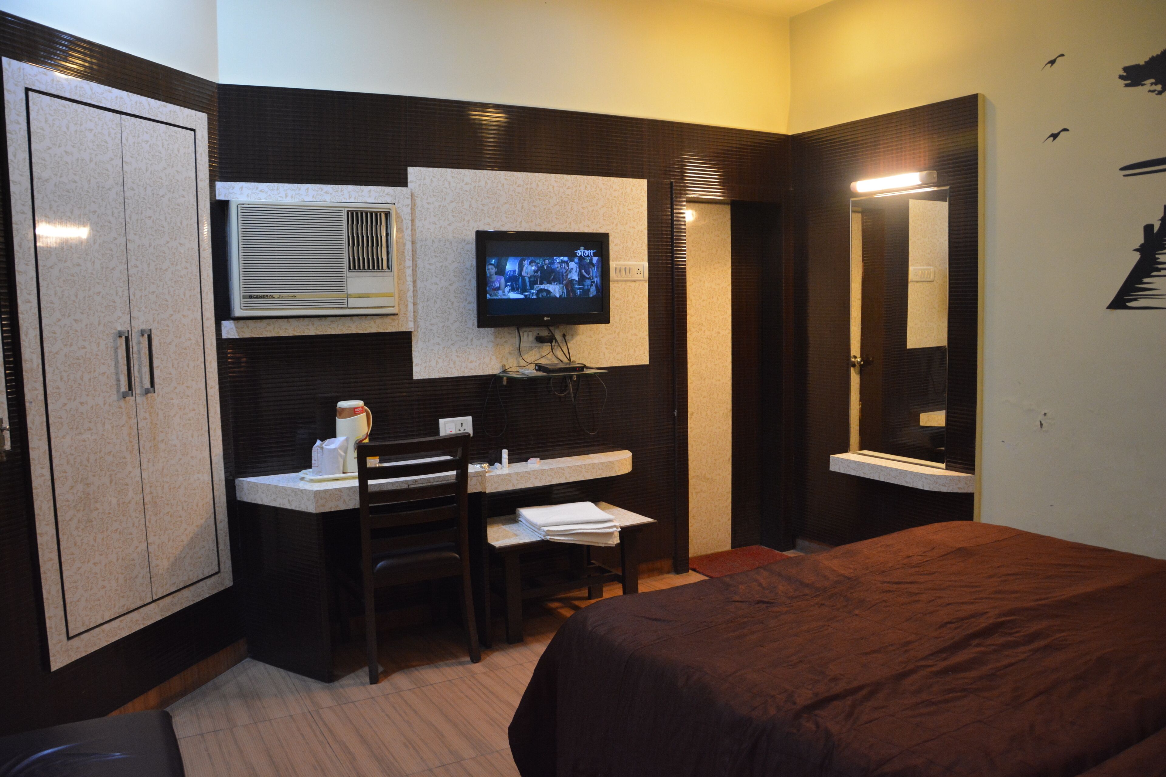 Una habitación de hotel con cama, escritorio, silla, televisor y armario.