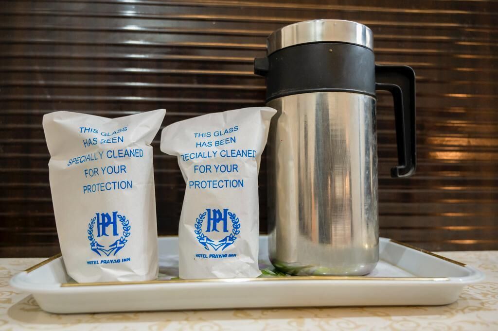 Two bags labeled "THIS GLASS HAS BEEN SPECIALLY CLEANED FOR YOUR PROTECTION" and a stainless steel thermos on a tray.