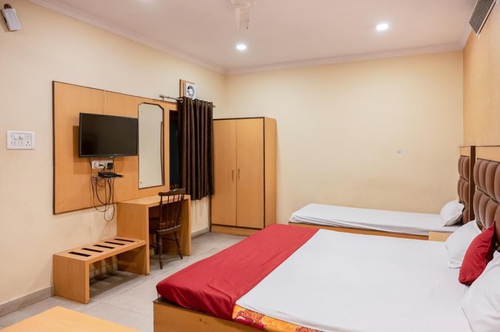 A hotel room with a bed, a desk with a chair, a television, and a wardrobe.