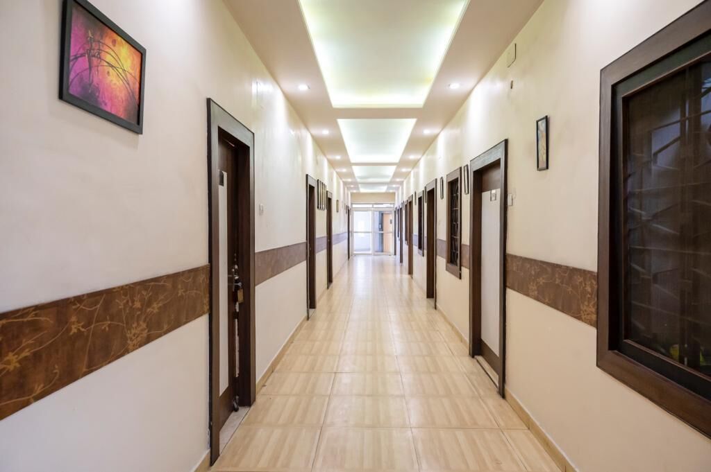 A long, well-lit hallway with doors on both sides, leading to individual rooms.