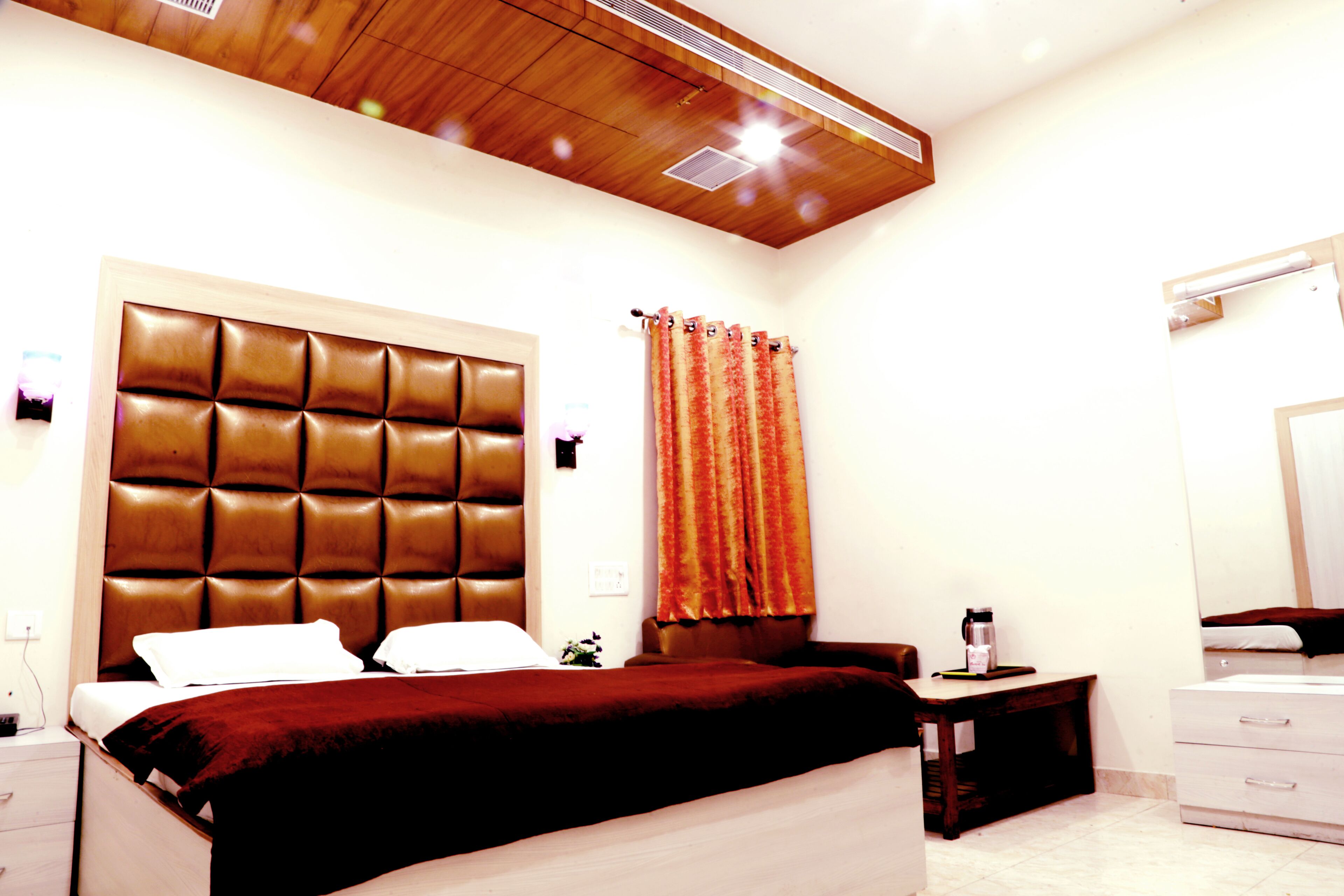 Une chambre d’hôtel avec un grand lit, un plafond en bois, une table de chevet avec une lampe et une salle de bain avec un miroir.