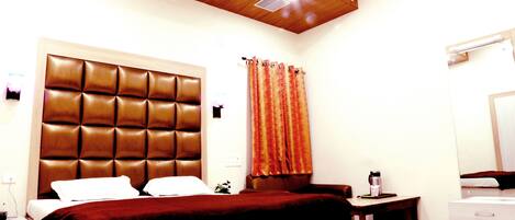 Une chambre d’hôtel avec un grand lit, un plafond en bois, une table de chevet avec une lampe et une salle de bain avec un miroir.