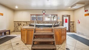 A sauna area with a wooden bench, a stone wall, and a door with a caution sign. - Cozy Ski In/Ski Out Artsy Studio Apt (Breckenridge)