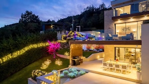 A modern house with a patio area, outdoor seating, and string lights. - Villa AltaVista - Seaview & Relax with Private MiniGolf & Wellness (Poljane)