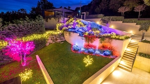 A modern outdoor area with a staircase, illuminated plants, and a well-maintained lawn. - Villa AltaVista - Seaview & Relax with Private MiniGolf & Wellness (Poljane)