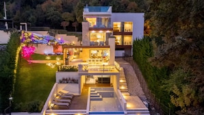 A modern two-story house with a well-lit outdoor area, including a staircase and seating area. - Villa AltaVista - Seaview & Relax with Private MiniGolf & Wellness (Poljane)