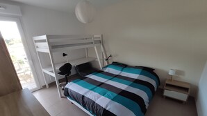 A bedroom with a bunk bed, a desk, a chair, a lamp, and a bedside table. - Central Apartment in Biscarrosse - 4 Guests, Close to Beaches, Surf Classes, Parking & Wifi Included (Biscarrosse)