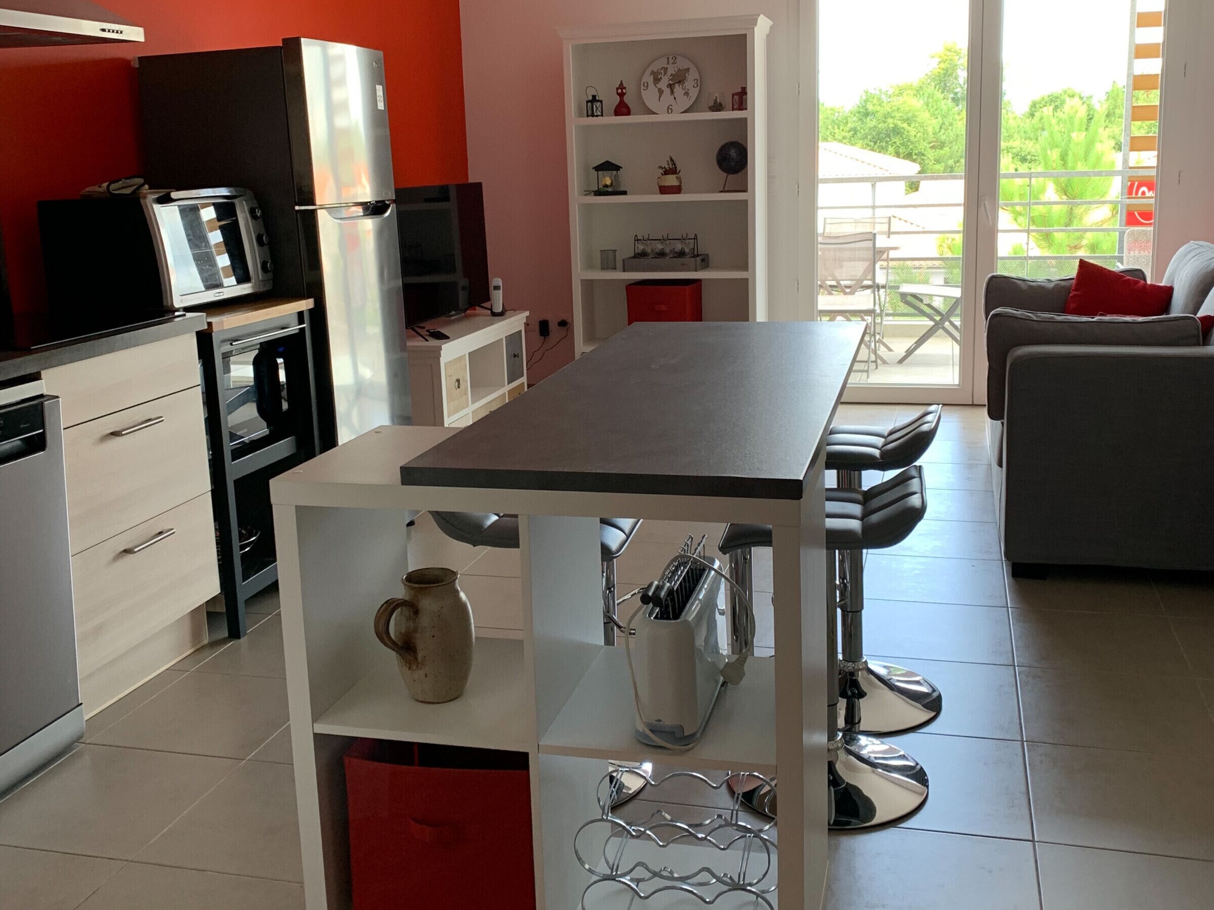 A modern kitchen with a central island, white cabinetry, and a red accent wall.