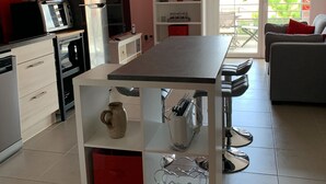 A modern kitchen with a central island, white cabinetry, and a red accent wall. - Central Apartment in Biscarrosse - 4 Guests, Close to Beaches, Surf Classes, Parking & Wifi Included (Biscarrosse)