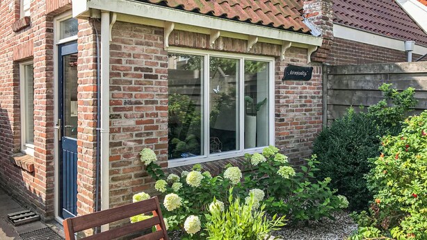 A brick building with a tiled roof, a wooden bench, and a sign reading "dunijcoffje". - Beach front home in Bergen aan Zee (Bergen aan Zee)